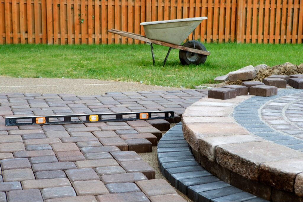 A paver patio and stone steps under construction during a landscape construction project 