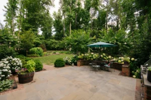 Bluestone patio with umbrella and hydrangeas designed for backyard summer entertaining