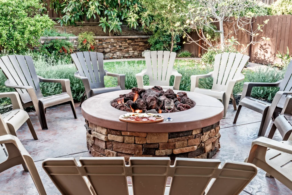 Stone firepit surrounded by chairs creating a lounge zone for backyard entertaining