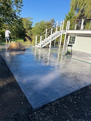 A stamped concrete patio being finished below a raised deck by JRD Landscape Design.