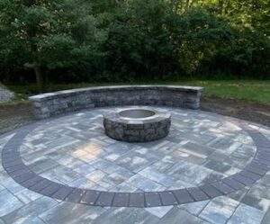 Circular stone patio with fire pit from JRD Landscape Design, showing hardscape and softscape balance.