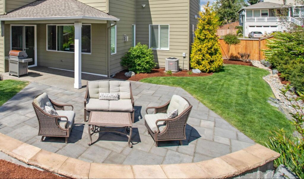 Backyard patio seating area framed by planting beds, mulch, and open lawn from JRD Landscape Design.